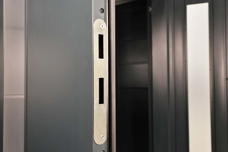 Innenansicht eines Metall-Gerätehauses mit Lüftungsschlitzen an der dunklen Wand und einer hellgrauen isolierten Decke.