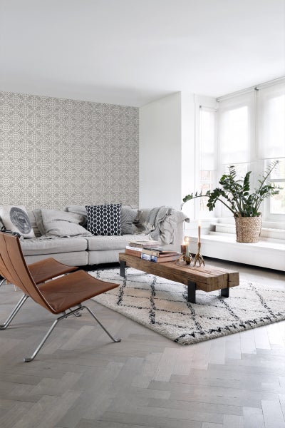 Wohnzimmer mit Sofa, Sessel, Teppich, Couchtisch und gemusterter Tapete.