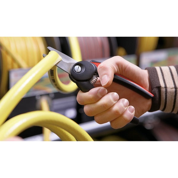 Eine Hand schneidet ein gelbes Kabel mit einer Kabelschere