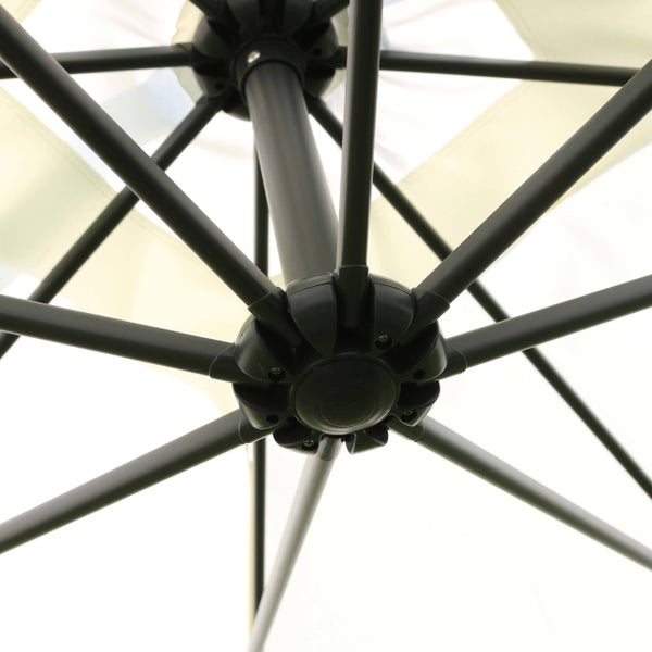 Detailansicht der Metallstreben und des Nabensystems an der Unterseite eines Sonnenschirms mit hellem Stoff.