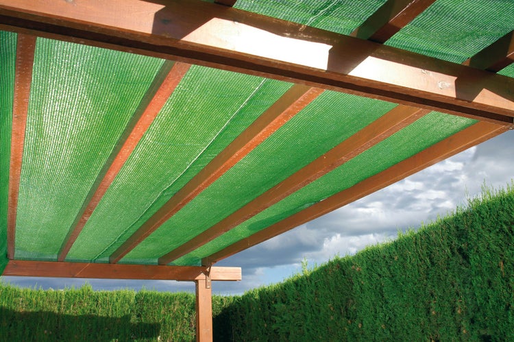 Grünes Schattiernetz als Sonnenschutz auf einer Holzpergola im Garten.