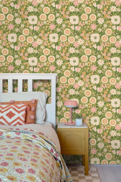 Vliestapete mit retro Blumenmuster in einem Schlafzimmer mit weißem Holzbett, gelbem Nachttisch und rosa Tischlampe.