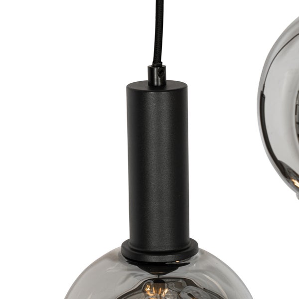 Detailansicht einer Pendelleuchte mit schwarzer Aufhängung und transparentem Glasschirm