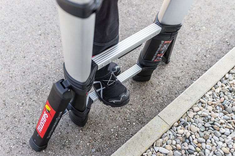 Person auf einer Teleskopleiter mit Aluminiumsprossen und schwarzem Fuß