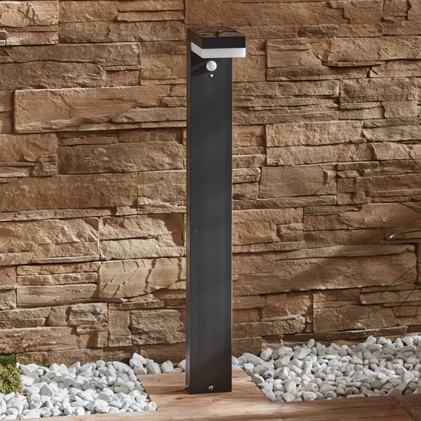Moderne Solar-Wegleuchte in Anthrazit mit Bewegungsmelder vor einer Steinwand.