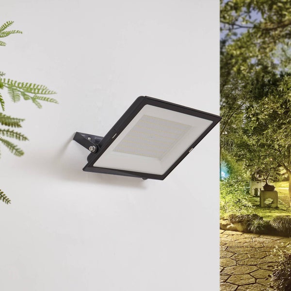Flacher LED-Außenstrahler in Schwarz, an einer Hauswand montiert, Blick auf einen Garten mit Steinweg.