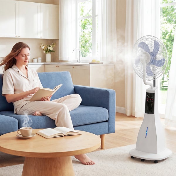 Eine Frau liest auf einem blauen Sofa in einem hellen Wohnzimmer, während ein weißer Sprühnebel-Standventilator für Abkühlung sorgt.
