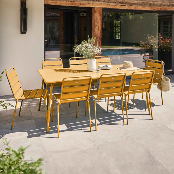 Modernes gelbes Garten-Essset aus Metall mit rechteckigem Tisch und acht Stühlen auf einer hellen Steinterrasse.
