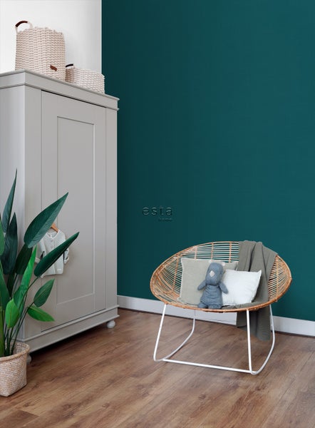 Kinderzimmer mit Kleiderschrank, Rattansessel und grüner Wand