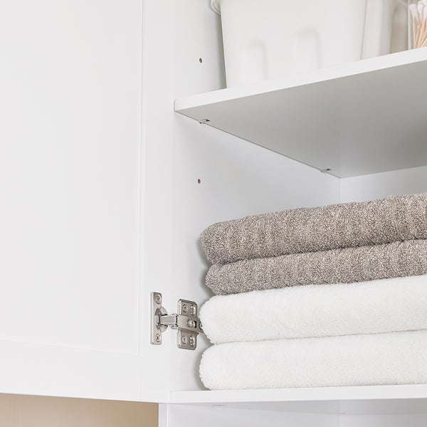 Geöffneter weißer Badezimmerschrank mit Handtüchern und Behälter