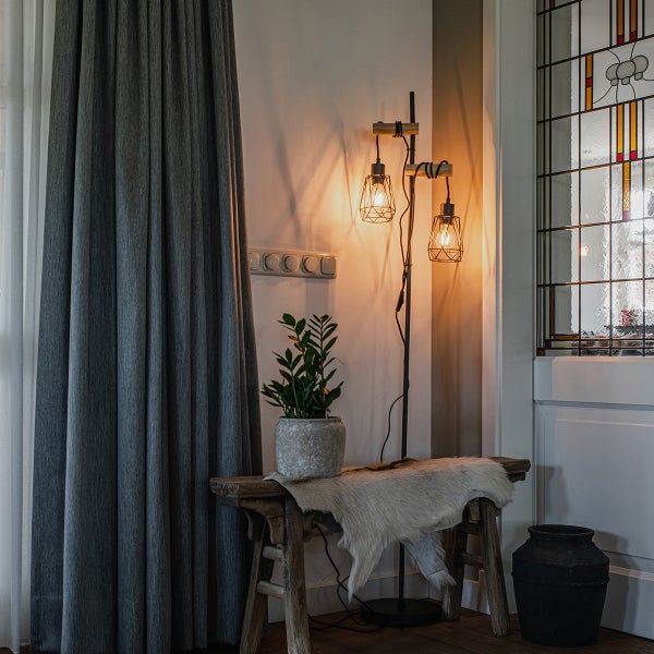 Dekorativer Wohnbereich mit Vorhang, Stehlampe und Zimmerpflanze