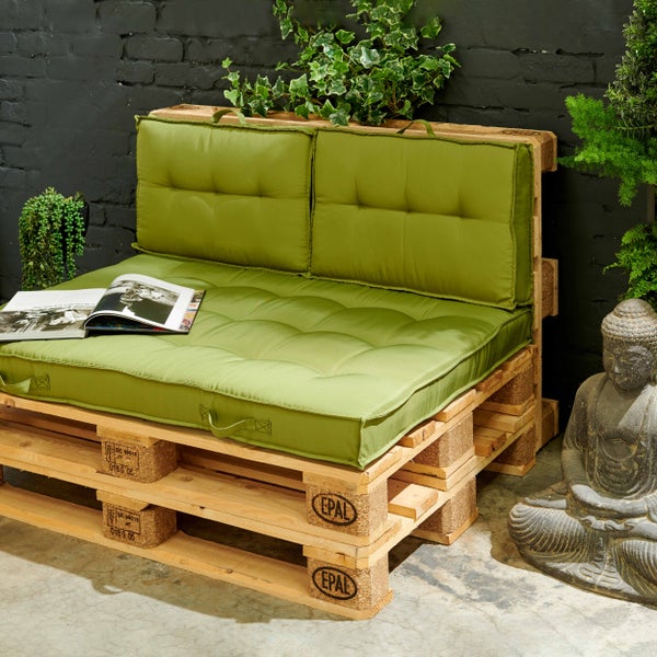 Palettenkissen Set mit Sitzauflage und zwei Rückenkissen auf einem Palettensofa aus Holz, dekoriert mit Pflanzen, einer Statue und einem Magazin.