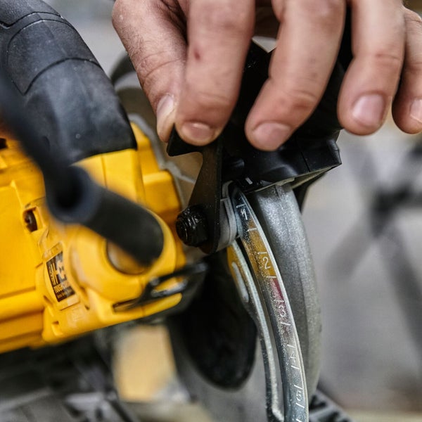 Detailansicht einer Hand, die eine Handkreissäge bedient, mit Fokus auf die Tiefeneinstellung