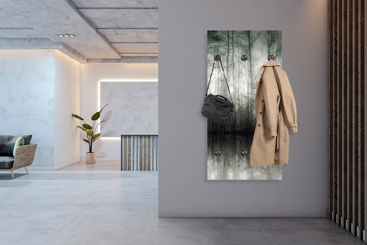 Dekorative Garderobe mit Waldmotiv, einer Handtasche und einem Trenchcoat in einem hellen, modernen Raum.