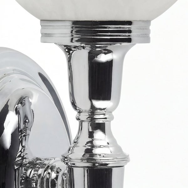 Detailaufnahme einer Badezimmerlampe mit Lampenschirm aus Glas und verchromtem Metallfuß