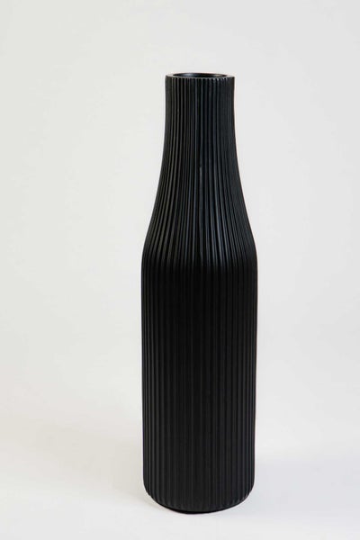 Schwarze Vase mit vertikaler Riffelstruktur in Flaschenform.