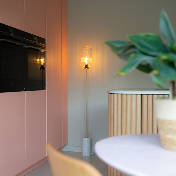 Stehlampe mit Marmorfuß und geripptem Glasschirm in einem modern eingerichteten Raum