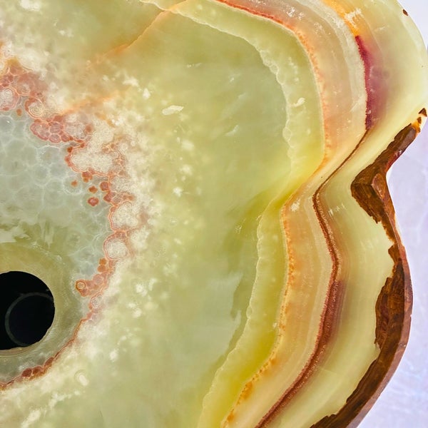 Detail eines grünen Aufsatzwaschbeckens aus Onyx-Naturstein mit Ablauföffnung, Maserung und polierter Oberfläche.