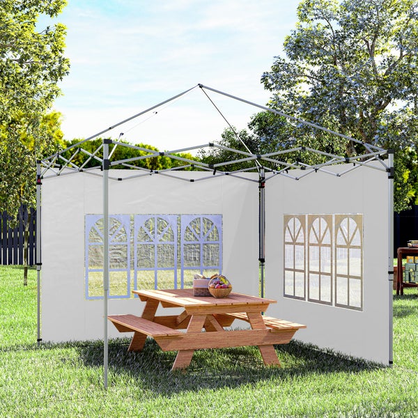 Faltpavillon-Gestell mit zwei weißen Seitenwänden inklusive Sprossenfenstern über einer hölzernen Picknickgruppe im Garten.