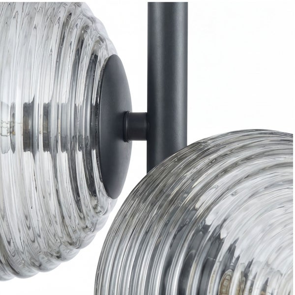 Detailaufnahme einer Wandleuchte mit geriffelten Glasschirmen und einem schwarzen Metallgestell