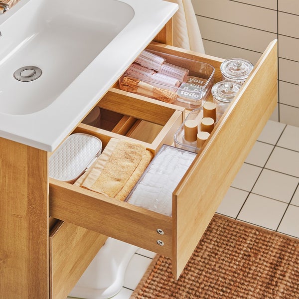 Offene Holzkommode unter einem Waschbecken mit Badutensilien