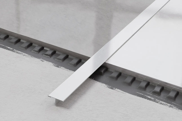 Detailaufnahme einer silberfarbenen Fliesenschiene auf Fliesen