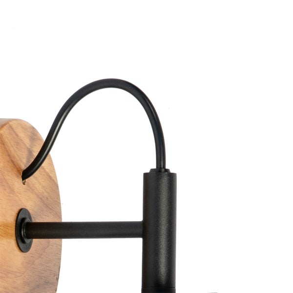 Detailansicht einer Wandleuchte mit runder Holzbasis, schwarzem Metallarm und schwarzem Kabel.