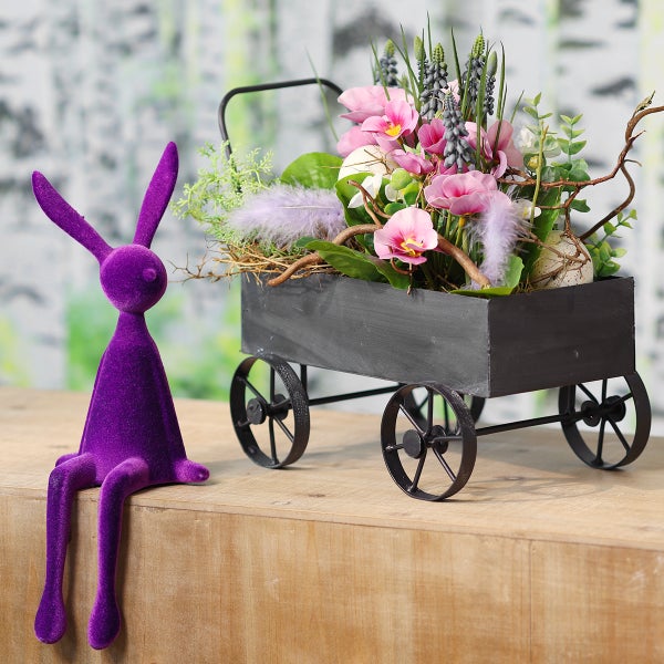Dekoration mit lila Hase und Blumenwagen mit Blumendekoration