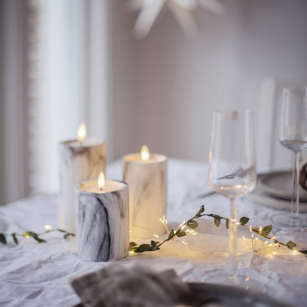 Tischdekoration mit LED-Kerzen in Marmoroptik, Lichterkette und Weingläsern für eine festliche Atmosphäre