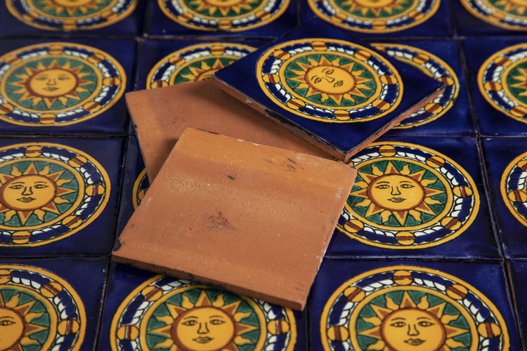 Mehrere blaue Fliesen mit Sonnendesign und unglasierte Terrakottafliesen