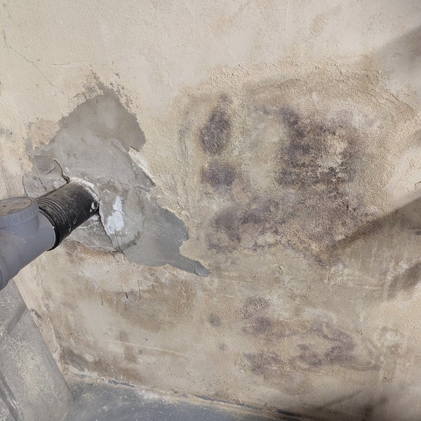 Beschädigte Wand mit Feuchtigkeit und Schimmelbildung neben einem Rohr