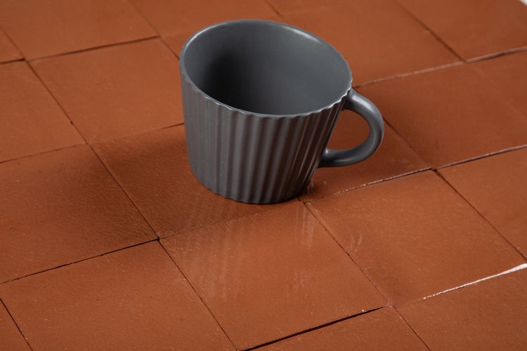 Quadratische Bodenfliesen in Kombination mit einer Tasse.