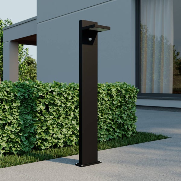 Moderne Wegeleuchte in Anthrazit mit Bewegungsmelder an einem Gartenweg vor einer Hecke und einer modernen Hausfassade.
