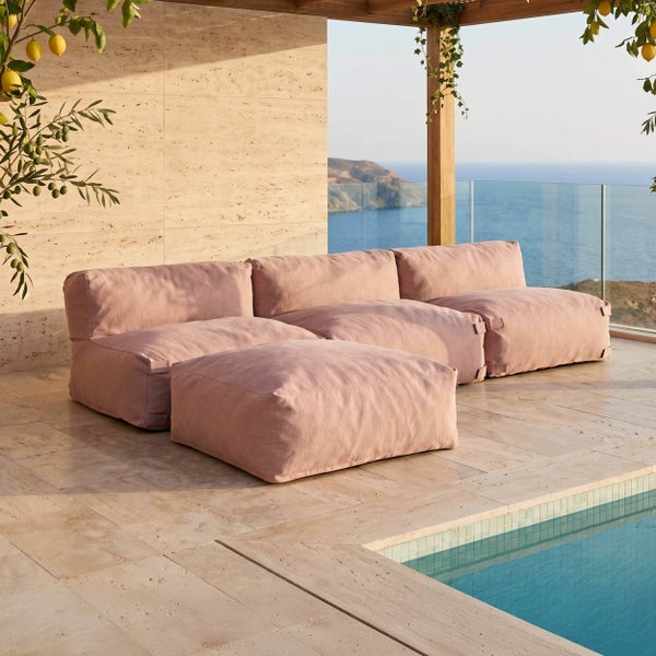 Modulares Outdoor-Lounge-Sofa-Set aus Stoff mit drei Sitzelementen und Hocker auf einer Steinterrasse mit Pool und Meerblick.