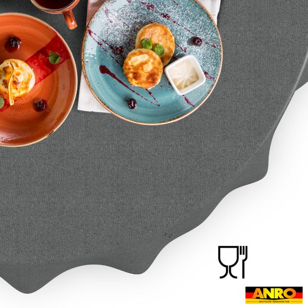 Rundes, graues Tischtuch mit Stoffstruktur, lebensmittelecht, gedeckt mit Frühstückstellern. ANRO Logo.