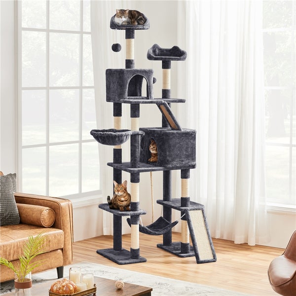 Kratzbaum mit mehreren Ebenen, Höhlen, Liegeflächen, Hängematte und Spielzeug für Katzen in einem Wohnzimmer.