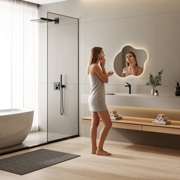 Modernes Badezimmer mit freistehender Badewanne, begehbarer Dusche mit schwarzen Armaturen, Waschtisch mit LED-Spiegel und Holzregal.