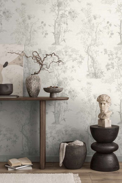 Vliestapete mit floralem Baum und Vogel Motiv im Landhausstil. Innenraum mit Holzkonsolentisch, Dekoration, Skulptur und gemusterter Tapete.