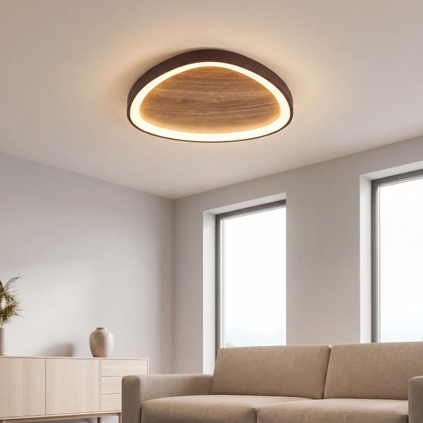Moderne LED-Deckenleuchte in organischer Dreiecksform mit Holzoptik montiert in einem hellen Wohnzimmer.