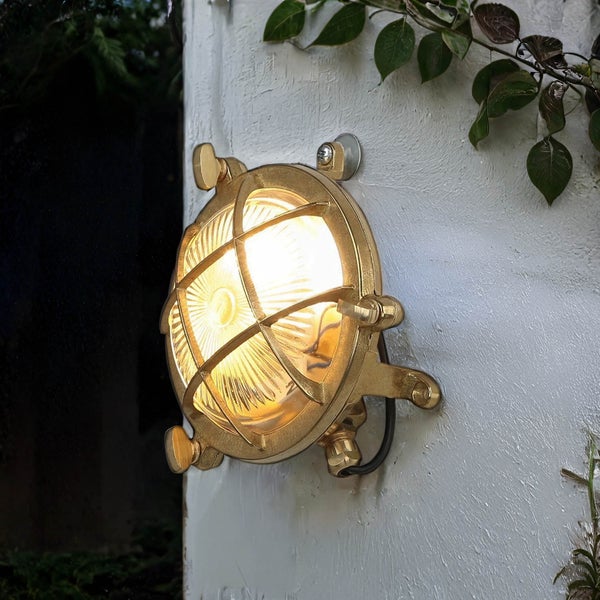 Runde Außenleuchte aus Metall mit Schutzgitter an einer Wand