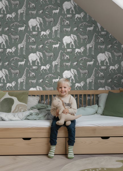 Helle Kinderschlafzimmer Szene mit Vliestapete mit Safari Tiermotiven hinter einem Funktionsbett aus Holz.