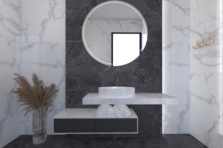 Modernes Badezimmer mit rundem Spiegel, Waschtisch, Handtüchern und dekorativem Gras