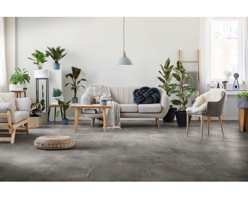 Helles Wohnzimmer mit großformatigen Fliesen in Steinoptik, modernem Sofa, Sessel und zahlreichen Zimmerpflanzen in einem offenen Wohnbereich.