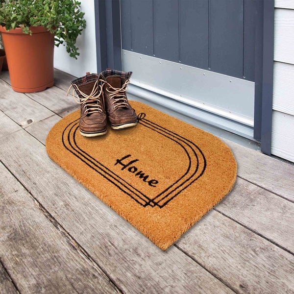 Fußmatte aus Kokosfaser mit der Aufschrift Home vor einer Haustür mit Schuhen