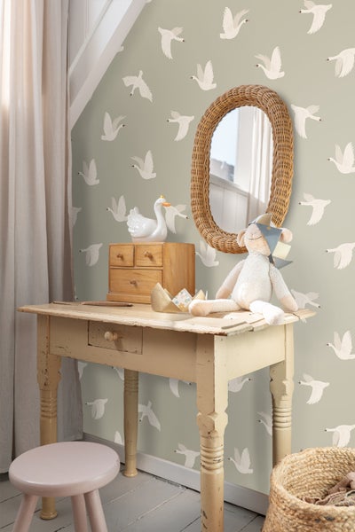 Szene mit Tisch, Spiegel und Dekoration im Kinderzimmer mit Tapete mit Schwanenmuster
