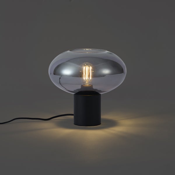 Moderne Tischleuchte mit schwarzem zylindrischem Sockel und rauchgrauem Glasschirm inklusive leuchtendem Filament-Leuchtmittel.