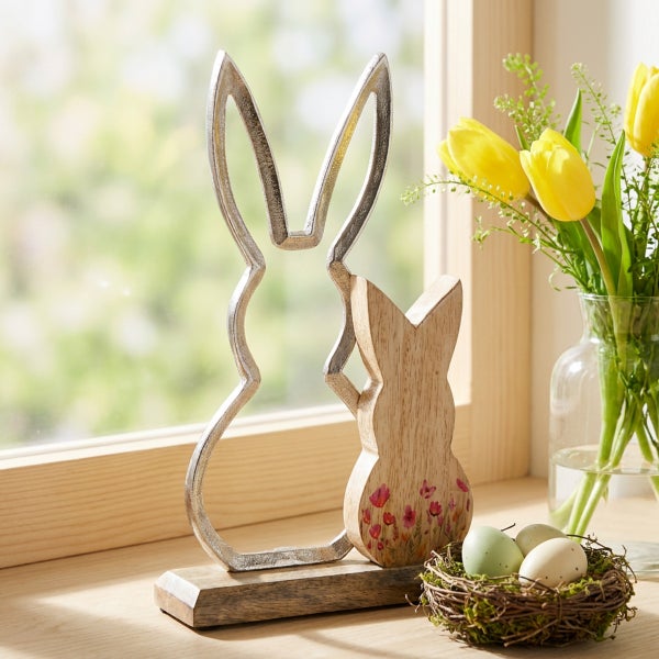 Osterhasen Deko-Aufsteller aus Metall und Holz mit floralem Muster auf einer Holzbasis neben einer Vase mit Tulpen und einem Nest mit Eiern