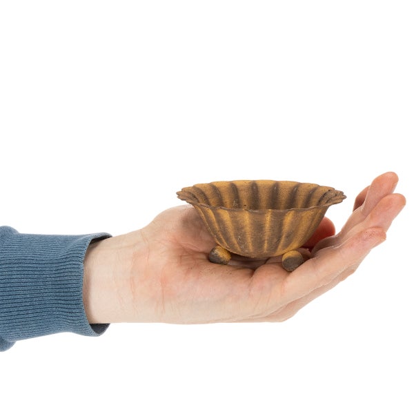 Kleine dekorative Metallschale in Rostoptik mit gewelltem Rand und Füßen, zur Größenveranschaulichung in einer Hand gehalten.