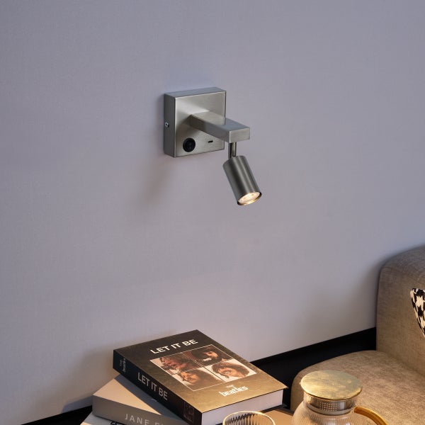 Wandleuchte aus Metall neben einem Nachttisch mit Buch