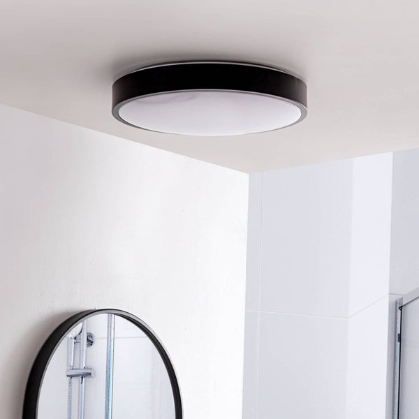 Moderne runde Deckenleuchte mit schwarzem Rahmen und weißem Diffusor, montiert in einem hellen Badezimmer über einem Spiegel.